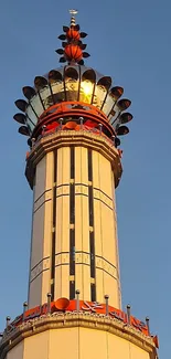 A majestic tower glowing golden against a blue sky, ideal for mobile wallpaper.