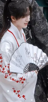 Person in traditional attire holding a decorative fan.