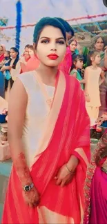 Woman in elegant red saree at a vibrant cultural event.