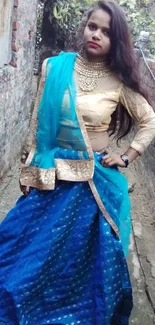 Woman in blue and gold traditional attire posing in a scenic alley.