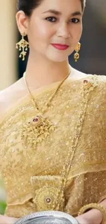 Elegant woman in traditional golden attire holding a silver tray.