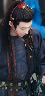 Person in traditional attire with intricate design on navy blue fabric.