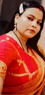 Woman in red and gold traditional saree, posing elegantly.