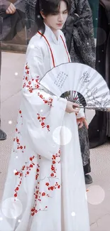 Traditional Chinese attire with fan and floral patterns.