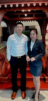 Elegant couple standing in a traditional wooden interior with dragon carvings.