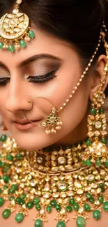 Woman adorned with traditional gold and emerald jewelry, elegant portrait wallpaper.