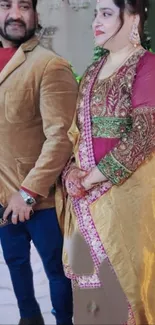 Couple in elegant, traditional outfits with vibrant colors.