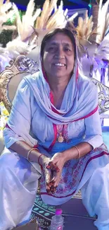 Elegant woman in traditional attire seated on an ornate chair.