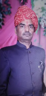 Traditional portrait with red turban and dark suit on colorful floral background.