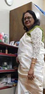 Elegant woman in white saree standing in a room.