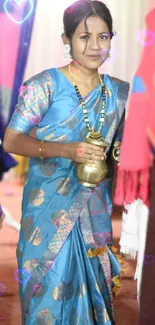 Woman in a blue saree holding a brass pot, showcasing traditional attire.