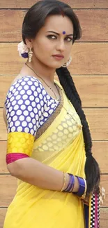 A woman in a vibrant yellow saree with a traditional look.