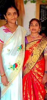 Two women in colorful traditional sarees with intricate design.