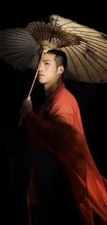 Man in red robe with an umbrella against a black background.