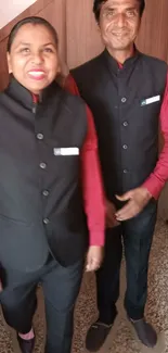 Elegant duo in black and red uniforms standing confidently.