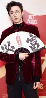 Person in velvet jacket holding fan on red background.