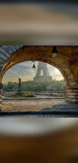 Paris Eiffel Tower viewed through stone archway at dawn.