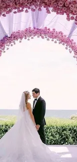 Romantic wedding arch with pink roses and couple during ceremony.