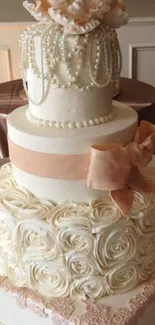 Three-tier wedding cake with rose icing and peach bow.