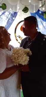 Bride and groom standing under floral arch at wedding ceremony.