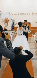 Bride and groom embracing at their elegant wedding ceremony, surrounded by photographers.