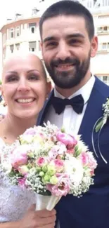 Smiling wedding couple with floral bouquet, embracing in elegant attire.