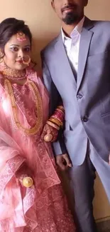 Elegant wedding couple in traditional attire with pink and gray hues.