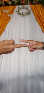 Wedding rings gesture with gold curtain backdrop.