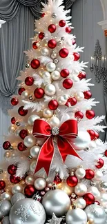 White Christmas tree with red and silver ornaments in elegant setting.