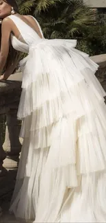 Elegant woman in layered white gown set against classical architecture.