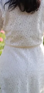 Woman in white lace dress standing in a flower field.