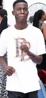 Young man wearing a white graphic tee at an event.