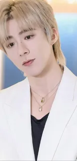 Person in a white suit with blonde hair and stylish jewelry.