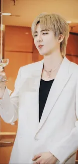 Stylish individual in a white suit holding a glass, perfect mobile wallpaper.