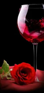 Red wine glass with a rose and petals on dark background.