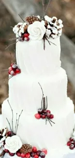 Three-tiered white cake with berries and pinecones.