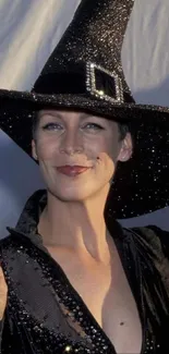 Woman in a shimmering black witch costume with an elegant pointy hat.