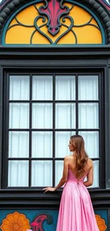 Woman in pink dress standing by a colorful window.