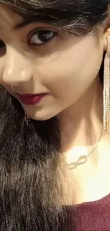 Close-up of a woman with long dark hair and elegant earrings.