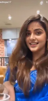 Woman in blue saree smiling elegantly.