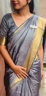 Woman in gray saree with golden accents on rainy day.