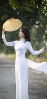 Woman in white dress holding a hat, surrounded by lush greenery.