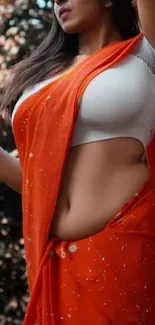 Woman in vibrant orange saree posing elegantly.