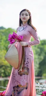 Woman in pink dress holding flowers by green backdrop.