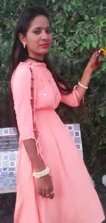 Woman in pink dress holding colorful leaves.