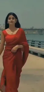 Woman in red saree walking by the river.