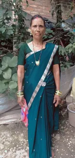 Woman in a blue sari with nature backdrop, showcasing culture and tradition.