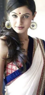 Elegant woman in a white saree with intricate details and jewelry.