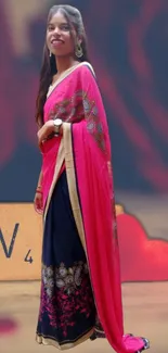 Woman in vibrant pink sari with intricate gold designs.