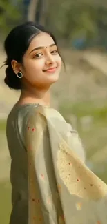 Woman in traditional attire smiling amidst nature.